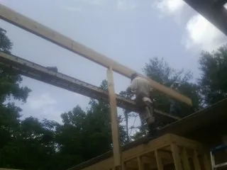 Carpenter setting a ridge beam over a new addition frame — Ice Dam Removal by Roofing Brothers in Interlochen