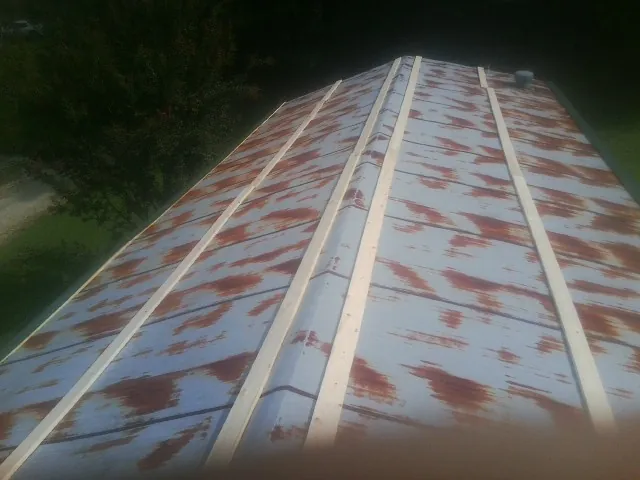 Rusted metal roof panels with new wood purlins before replacement — Storm Damage Roof Repair in Interlochen by Roofing Brothers