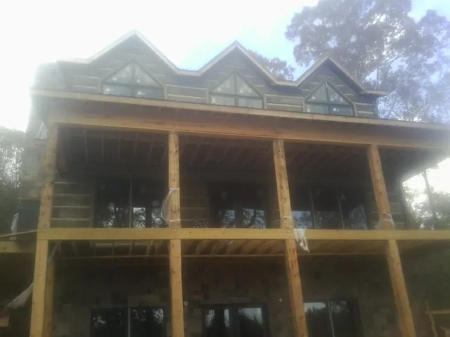 Dormers and porch framing on a large log home under construction — Roof Coating work by our crew in Interlochen