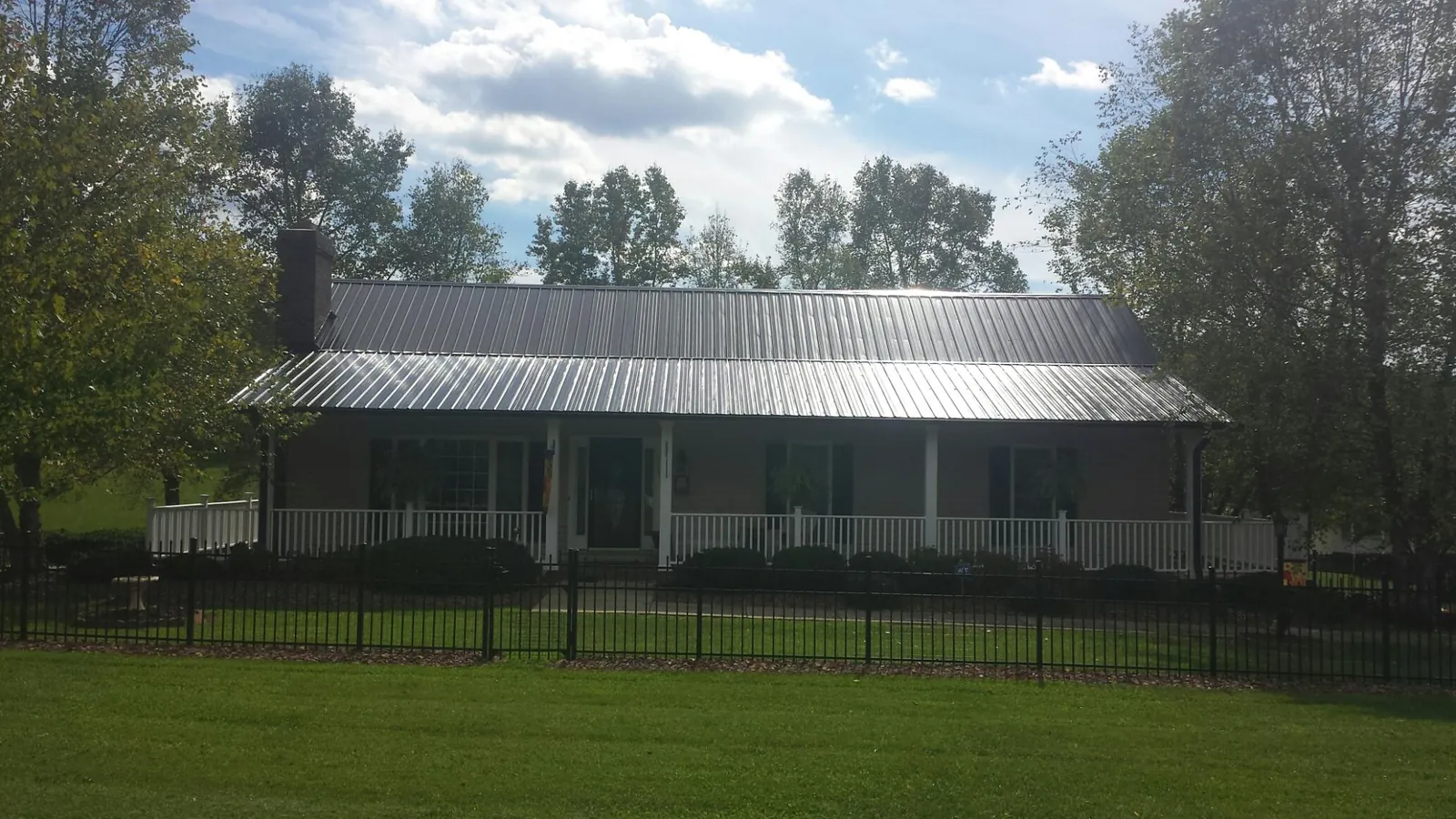 Gray metal roof on a brick ranch with a full width front porch — Gutter Guard Installation work by our crew in Interlochen
