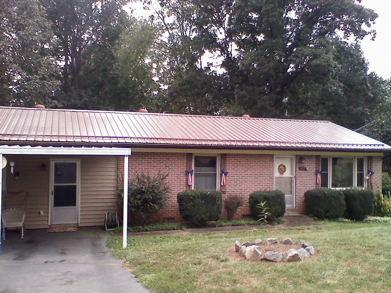Bronze metal roof and carport on a brick ranch home — Roof Repair work by our crew in Interlochen