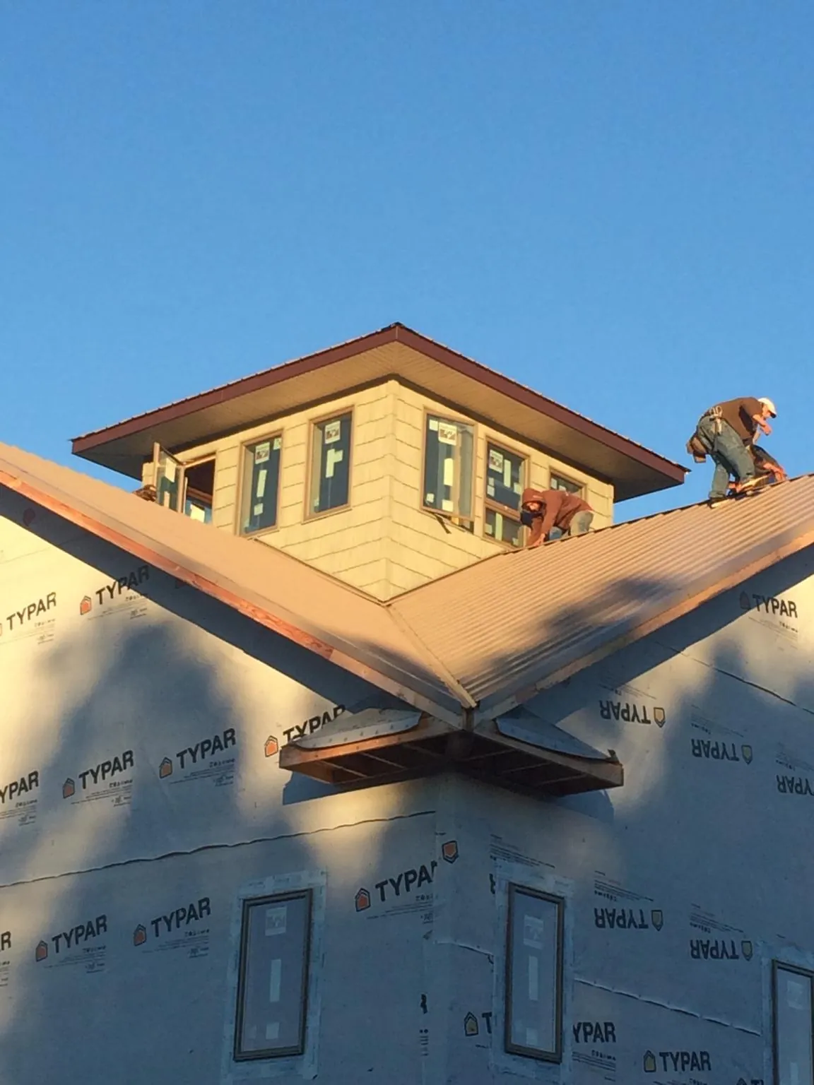 Roofers working around a rooftop cupola on a new metal roof at sunset — Roof Waterproofing in Interlochen by Roofing Brothers